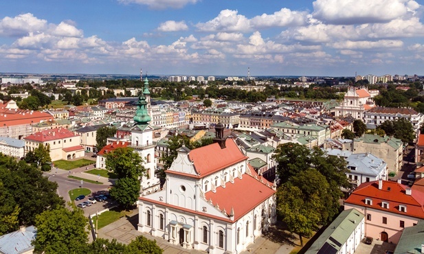 Zamość z lotu ptaka. Na pierwszym planie kolegiata. W tle skąpane w słońcu ulice przecinające się pod kątem prostym.