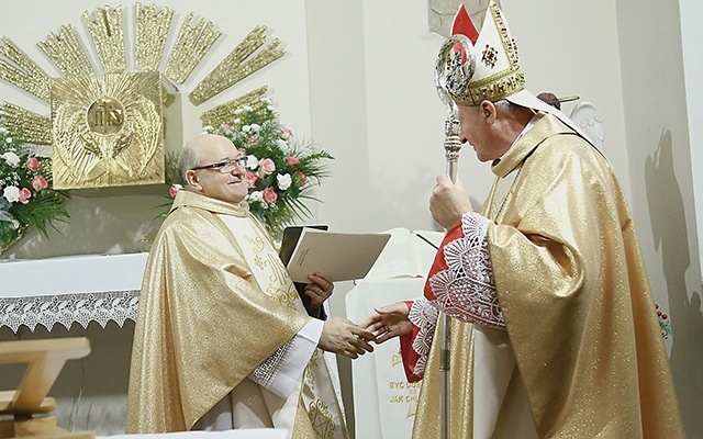 Biskup Andrzej Jeż wręcza proboszczowi, ks. Czesławowi Mazurowi dekret.