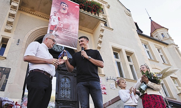 Łukasz Kaczmarek (w środku) przekazał swój medal jako wotum na ręce ks. Aleksandra Gondery (z lewej).