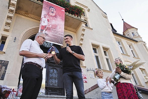 Łukasz Kaczmarek (w środku) przekazał swój medal jako wotum na ręce ks. Aleksandra Gondery (z lewej).