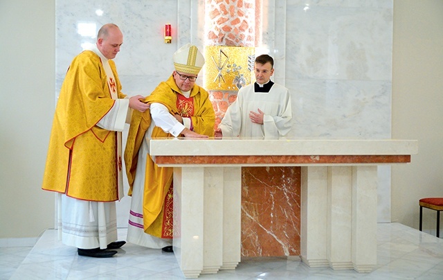 Bp Waldemar Musioł namaszcza mensę ołtarza krzyżmem.