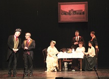 Z lewej stoją ks. Marek Noras jako Ebenezer Scrooge i ks. Jakub Dąbrowski jako Fred;  na prawo od nich siedzi żona Freda  – dr Katarzyna Musioł, ordynator oddziału pediatrii.
