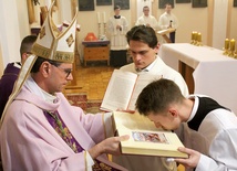Klerycy podchodzili do biskupa, który przekazywał im otwartą księgę Pisma Świętego.