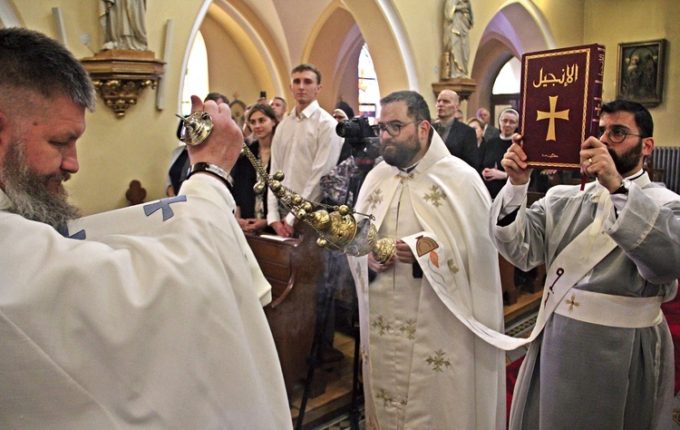 Diakon z Pismem Świętym obchodzi świątynię i jest okadzany przez jednego z kapłanów.