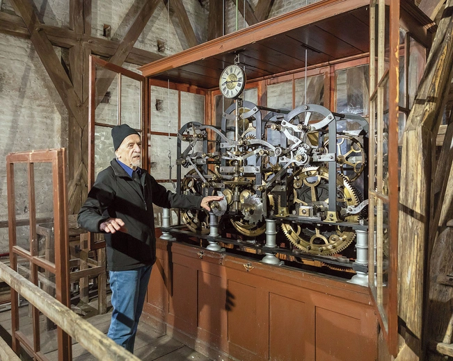 Andrzej Bochniak przy sercu zegara. Precyzyjne zębatki poruszają wielką wskazówką na wieży i dwoma młotami uderzającymi w gongi.
