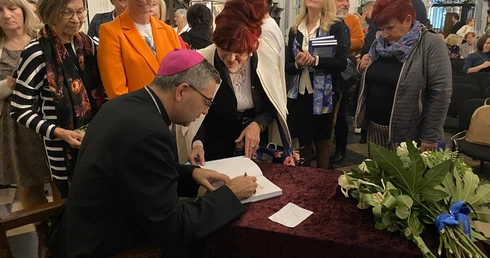 Podczas spotkania bp W. Osial podpisywał swoją publikację.