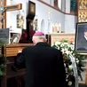 Biskup modli się przy trumnie zmarłego.