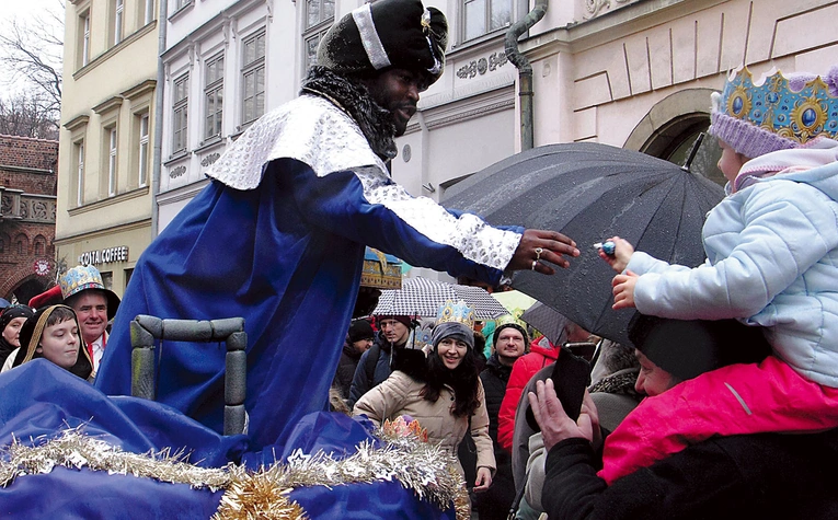 Król afrykański w drodze do stajenki śpiewa kolędy i rozdaje dzieciom cukierki.
