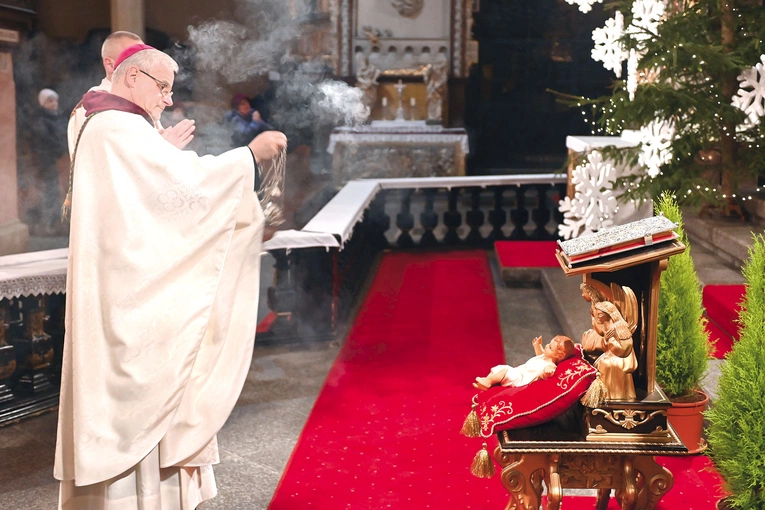 Bp Marek Mendyk okadza figurkę Dzieciątka.