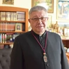 Ks. Józef Drabik z medalem, który otrzymują osoby należące do organizacji.
