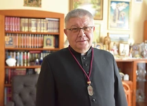 Ks. Józef Drabik z medalem, który otrzymują osoby należące do organizacji.