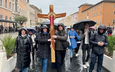 Pielgrzymi idą z krzyżem do bazyliki św. Piotra.