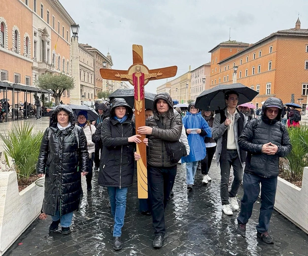 Pielgrzymi idą z krzyżem do bazyliki św. Piotra.