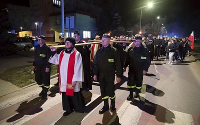 Zgromadzeni podążali za krzyżem, niosąc flagi i emblematy patriotyczne.