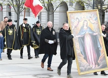 Mężczyźni noszą duży obraz  Matki Bożej Łaskawej  i sztandar św. Andrzeja Boboli.