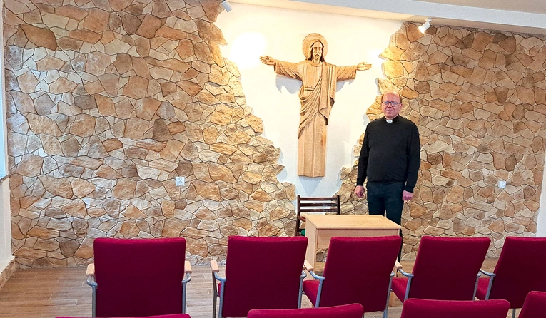 Ks. Jacek Wieczorek w sali z figurą Chrystusa Odkupiciela, wyrzeźbioną przez lokalnego artystę.