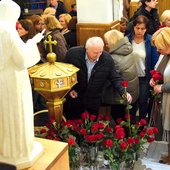 Wierni składają róże przed figurą świętej.
