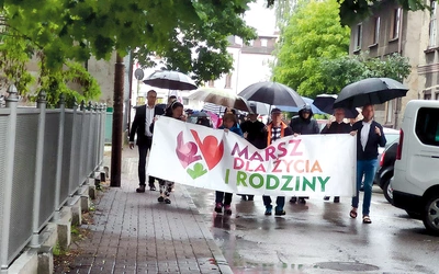 Wszyscy wytrwale maszerowali pod parasolami i w pelerynach.