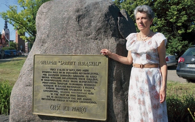 Grażyna Wosińska przy pomniku poświęconym ofiarom stalinowskiego terroru  po wydarzeniach z 17 lipca 1949 r.