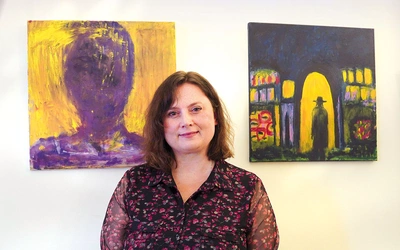 Agnieszka Paluch obok obrazów „Spotkanie Nikodema z Jezusem”  oraz „Autoportret”. 