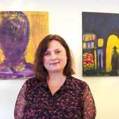 Agnieszka Paluch obok obrazów „Spotkanie Nikodema z Jezusem”  oraz „Autoportret”. 