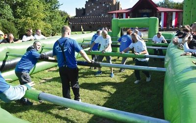 Uczestnicy zawodów grają w piłkę nożną w dmuchanym basenie.