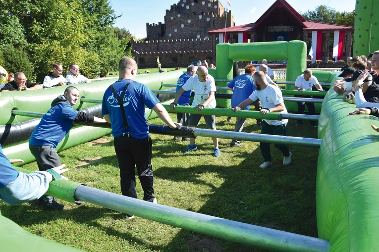 Uczestnicy zawodów grają w piłkę nożną w dmuchanym basenie.