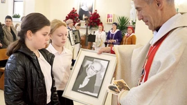 Dzieci ze szkoły w Łękawce w procesji z darami przynoszą zdjęcia ks. Jana Marszałka.