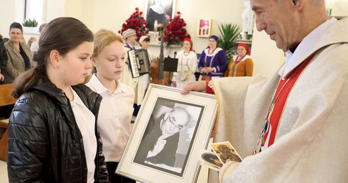 Dzieci ze szkoły w Łękawce w procesji z darami przynoszą zdjęcia ks. Jana Marszałka.