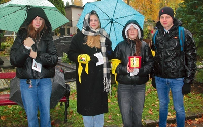 Zuzia, Michalina i Ola z ks. Rafałem kwestują na cmentarzu w Słupsku.