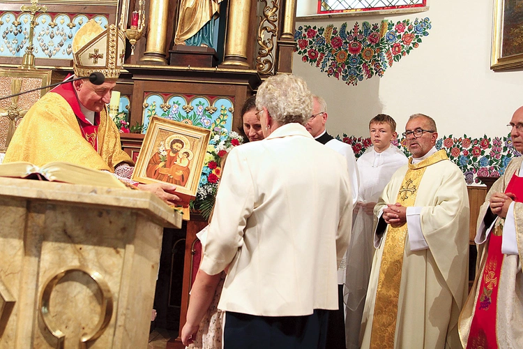 Biskup tarnowski Andrzej Jeż poświęconą ikonę patrona przekazuje pierwszej rodzinie, od której rozpoczęła się peregrynacja.