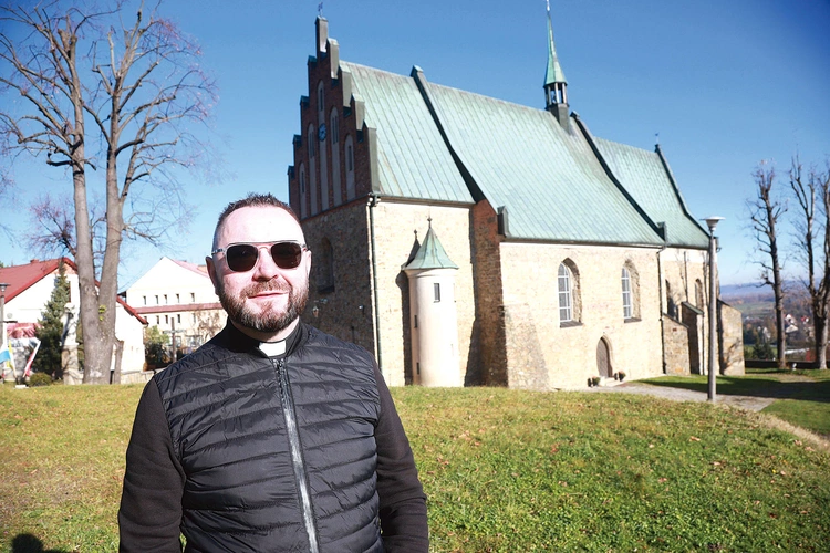 Ks. Rafał Słomba koło gotyckiego kościoła w Czchowie.
