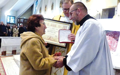 Grażyna Nalepa przyjmuje medal Stolicy Apostolskiej z rąk kanclerza ks. Adama Bieńka (z prawej). W środku, ze stosownym dyplomem – proboszcz ks. Stanisław Wójcik.