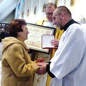 Grażyna Nalepa przyjmuje medal Stolicy Apostolskiej z rąk kanclerza ks. Adama Bieńka (z prawej). W środku, ze stosownym dyplomem – proboszcz ks. Stanisław Wójcik.
