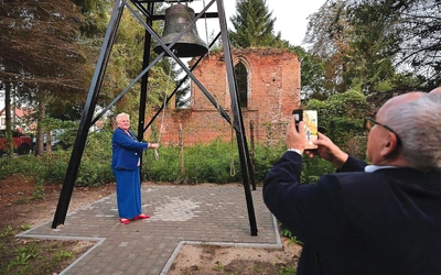 Historyczny dzwon, a w tle pozostałości gotyckiej budowli.