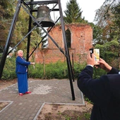 Historyczny dzwon, a w tle pozostałości gotyckiej budowli.