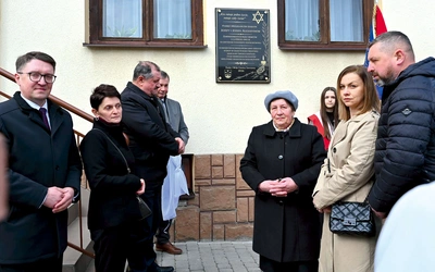 Krewni Augustynów i samorządowcy przed  odsłoniętą tablicą.